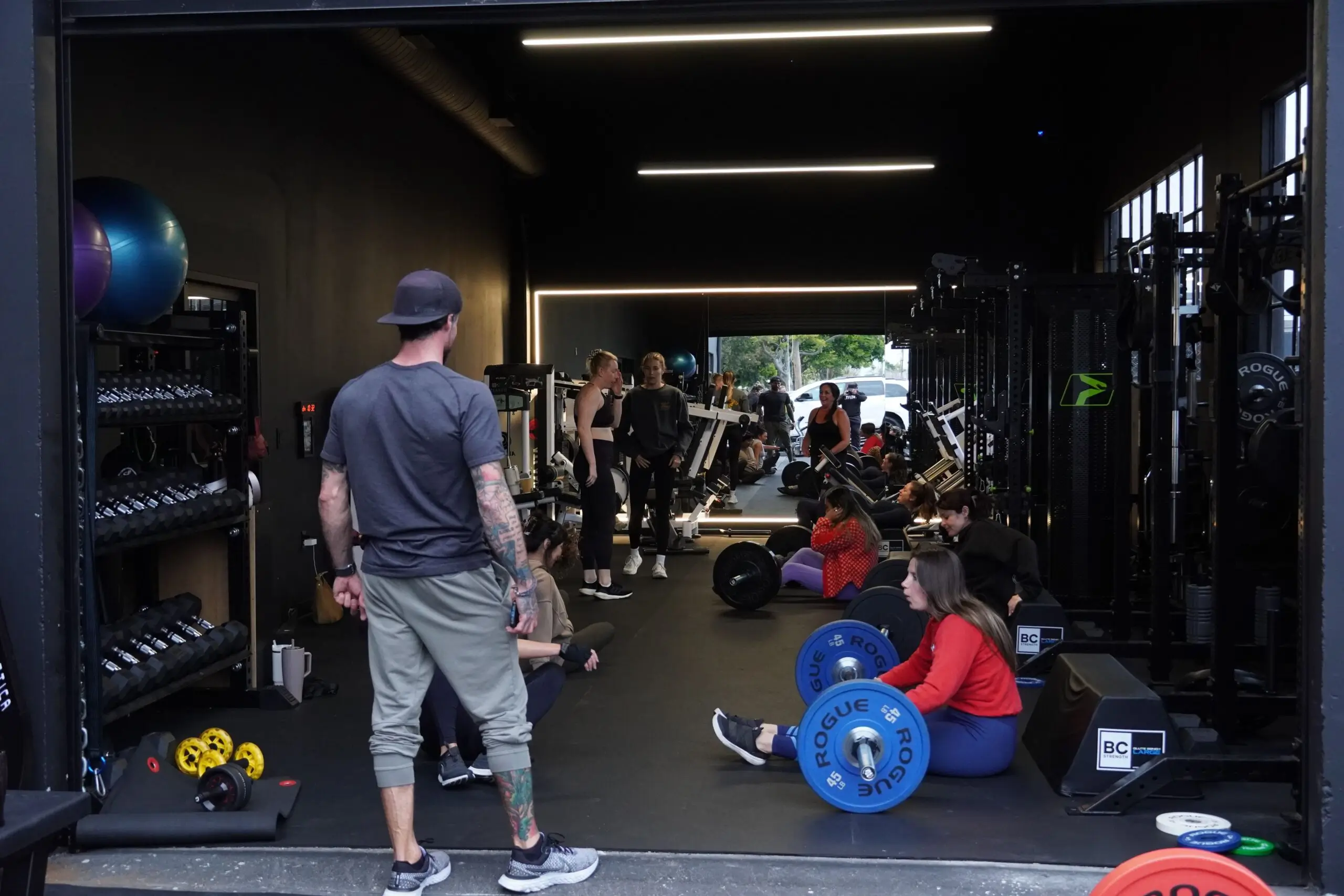 People participating in a group workout session inside a well-equipped strength training gym with various weights and machines.
